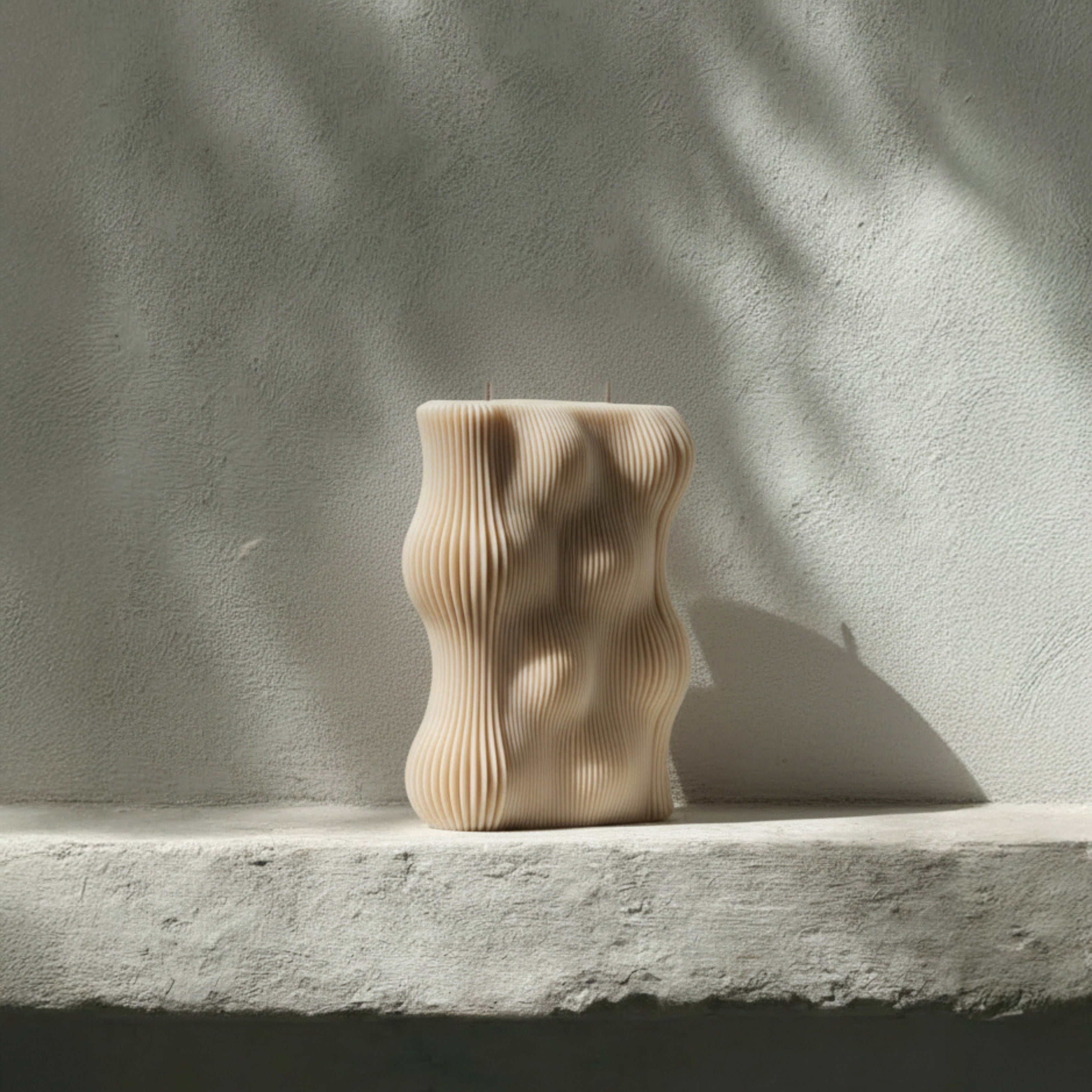 Sandstone wavy pillar candle by LAWA featuring soft neutral tone and curving texture
