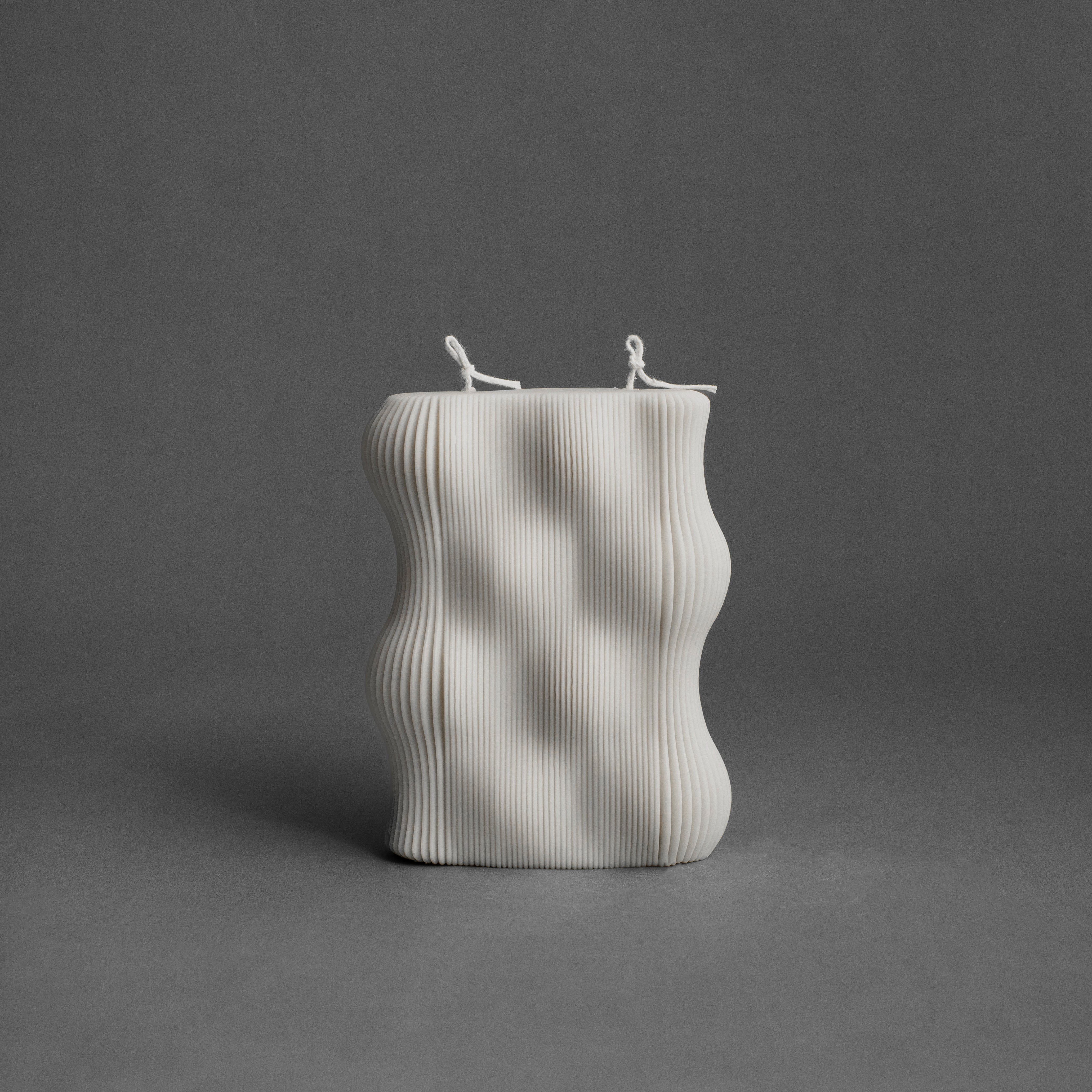 White wavy pillar candle by LAWA with a smooth flowing sculptural shape
