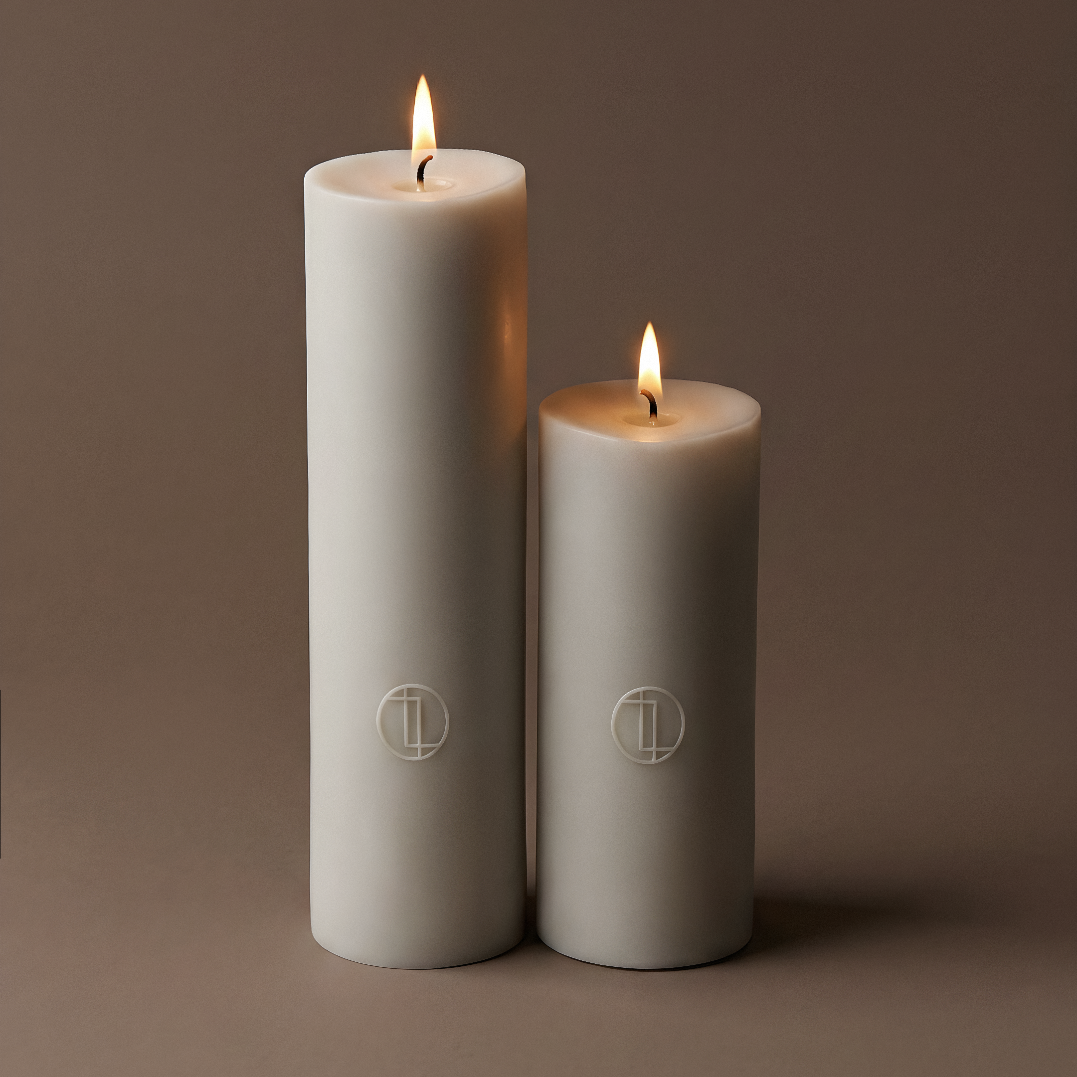Two white candles with a logo on a brown background